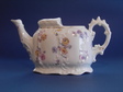 Medical (feeding-) cup in the shape of a tea pot. Fine china. Relief ornament. Colour flower pattern. Length 17 cm, height 9 cm. Probably Germany, ca. 1900